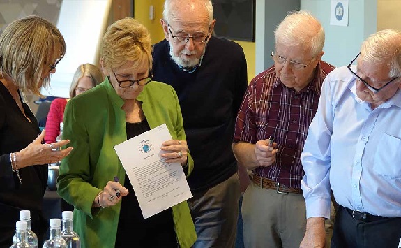 Five people, heads together, concetrating on some materials at an Engage FMS event